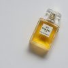 Elegant eau de parfum bottle with luxurious golden liquid on a minimalistic white background.